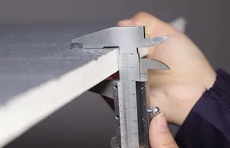 Worker measuring insulated panel thickness with calipers